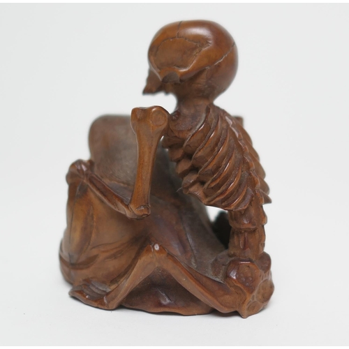 666 - Japanese carved boxwood okimono, formed as a skeleton on the back of a seated man, signed, 7.5cm