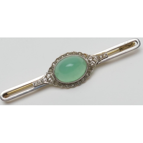 419 - Jade and diamond bar brooch, the celadon green cabochon bordered with rose cut diamonds set in white... 