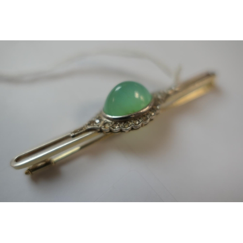 419 - Jade and diamond bar brooch, the celadon green cabochon bordered with rose cut diamonds set in white... 