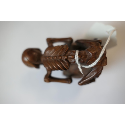 666 - Japanese carved boxwood okimono, formed as a skeleton on the back of a seated man, signed, 7.5cm