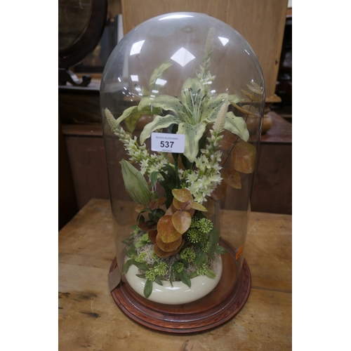 537 - Glass dome on a wooden base enclosing an artificial flower arrangement, height 47cm