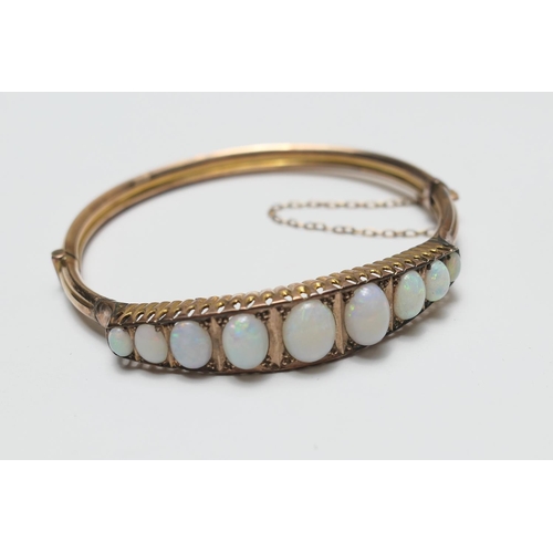 413 - Cabochon opal bangle, in 9ct gold, set with nine opals, the largest being 7mm x 6mm, 57mm (with an o... 