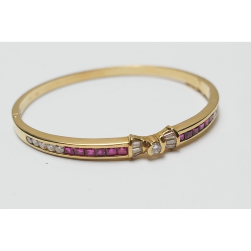 484 - Diamond and ruby bangle, in 18ct yellow gold, centred with a small brilliant cut diamond of approx. ... 