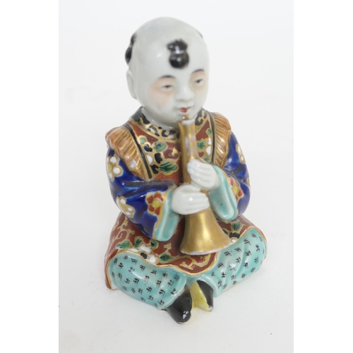 54 - Japanese Kutani porcelain model of a boy playing a horn, Meiji (1868-1912), decorated in rich colour... 