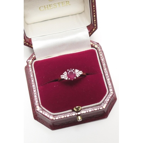 348 - Ruby and diamond cluster ring, in 18ct white and yellow gold, centred with an oval cut ruby of appro... 