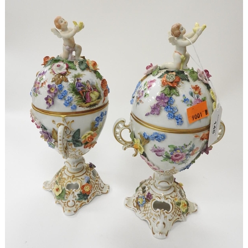 148 - Pair of Dresden floral decorated lidded and twin handled pots surmounted with cherubs