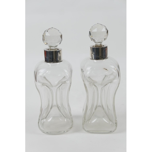 124 - Pair of silver mounted clear glass kluk-kluk decanters, the collars hallmarked Birmingham 1912, with... 