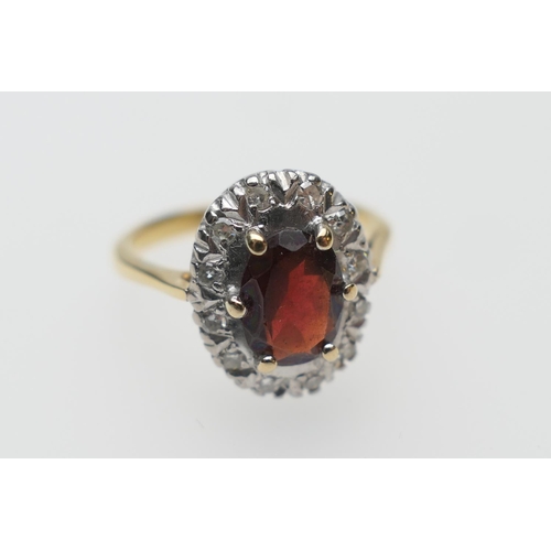 290 - Diamond and garnet cluster ring, the oval garnet of approx. 7mm x 5mm bordered with small round cut ... 