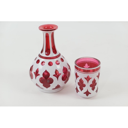 87 - Bohemian ruby and white overlay bottle carafe and beaker, the carafe 19cm (2)