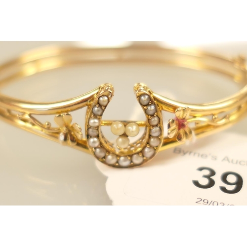 396 - 18ct gold and pearl bangle, worked with a horseshoe channel set with seed pearls and flanked with sh... 