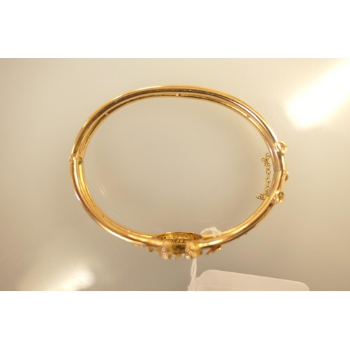 396 - 18ct gold and pearl bangle, worked with a horseshoe channel set with seed pearls and flanked with sh... 