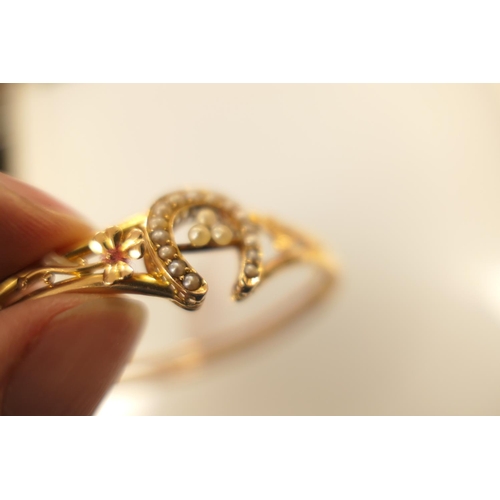 396 - 18ct gold and pearl bangle, worked with a horseshoe channel set with seed pearls and flanked with sh... 