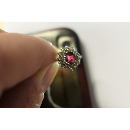 328 - Ruby and diamond cluster ring, the oval cut ruby of approx. 1ct, bordered with small round cut diamo... 