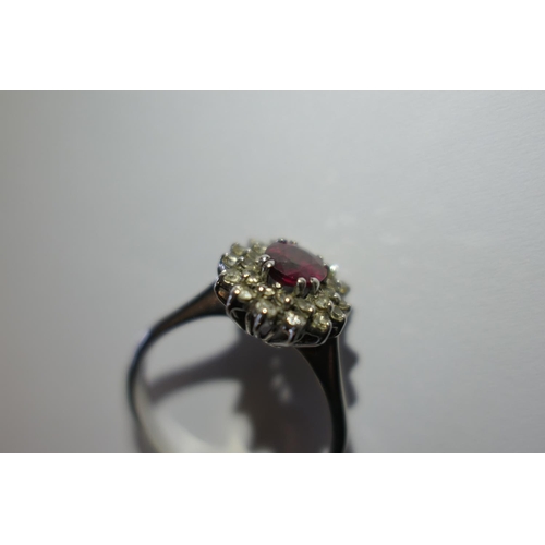 328 - Ruby and diamond cluster ring, the oval cut ruby of approx. 1ct, bordered with small round cut diamo... 