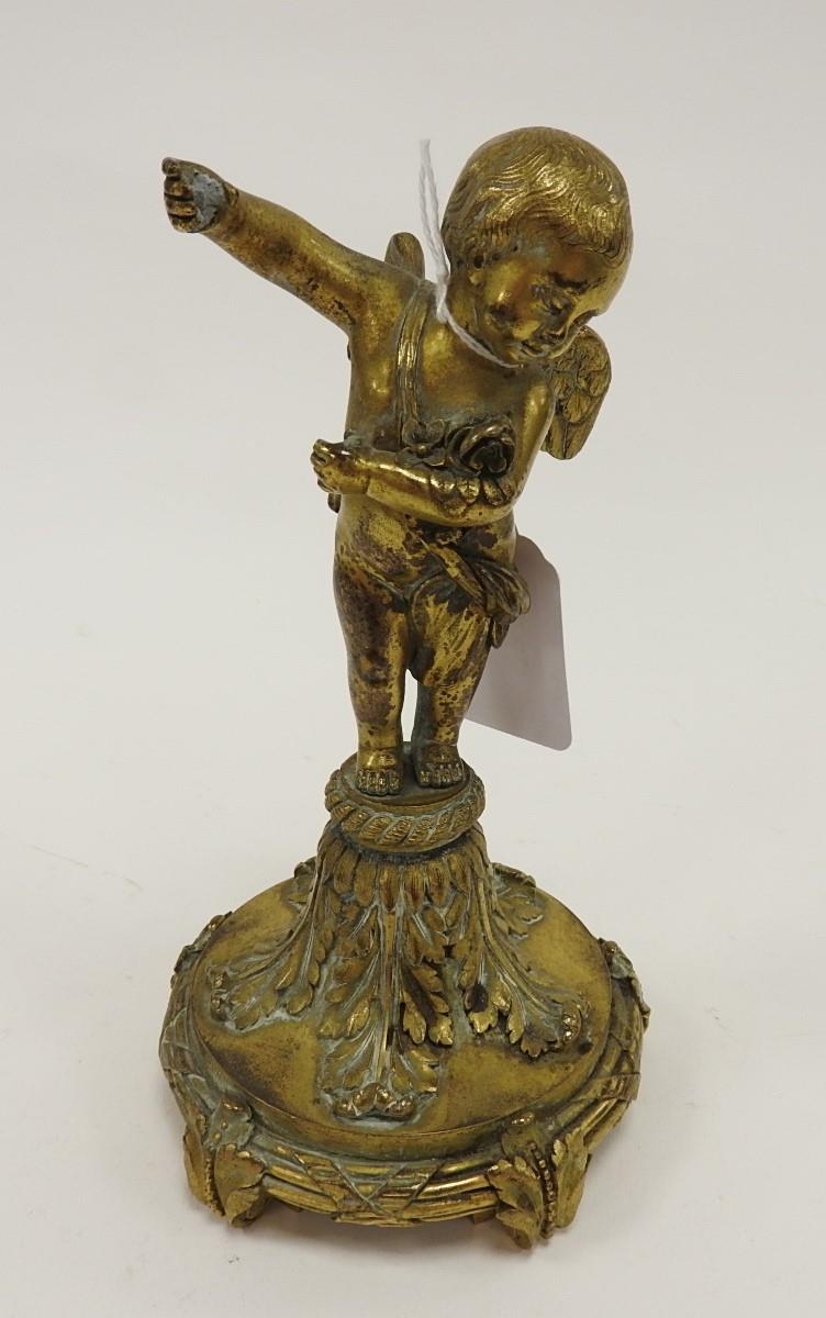 Brass cupid figure surmounted on a leaf scrolled five footed brass base