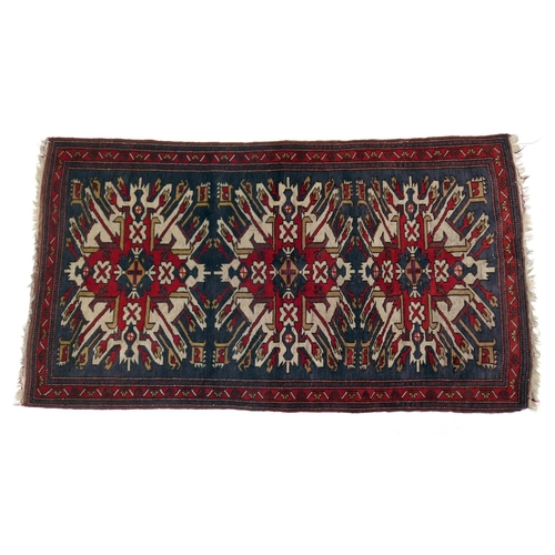 585 - Kazak rug, having three medallions in fawn, red and blue against an abrashed blue field with red run... 