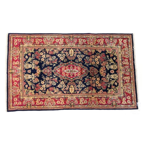 605 - Kashan rug, having a central elongated red reserve against a deep blue ground dispersed with flowers... 