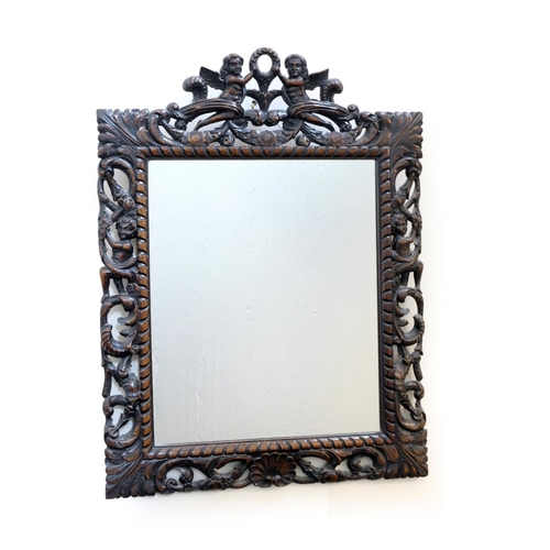 611 - Victorian carved oak wall mirror in Carolean style, carved with winged cherubs bordered with further... 