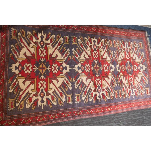 585 - Kazak rug, having three medallions in fawn, red and blue against an abrashed blue field with red run... 