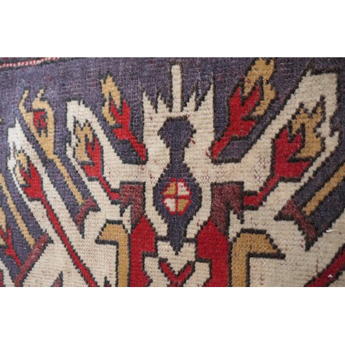 585 - Kazak rug, having three medallions in fawn, red and blue against an abrashed blue field with red run... 