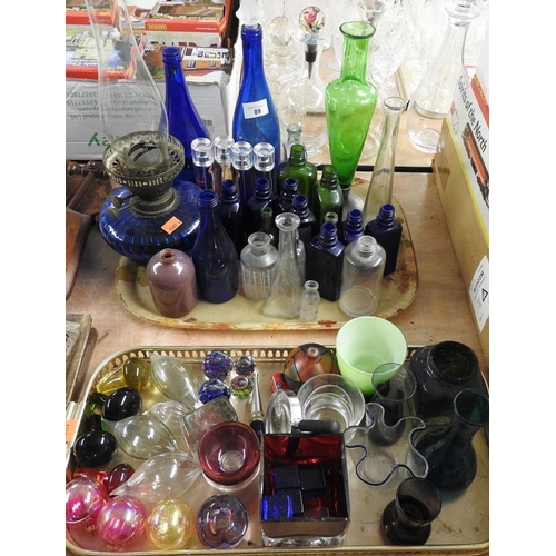 89 - Assorted coloured bottles, also a Victorian blue glass oil lamp, various glass baubles etc (2 trays)