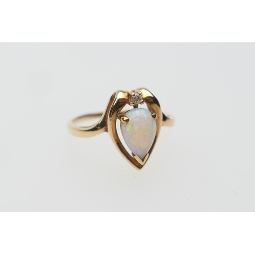 395 - Opal and diamond ring, in 10ct gold, set with a tiny brilliant cut diamond and a pear cut cabochon o... 