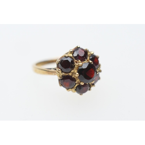 397 - Garnet cluster ring in 9ct gold, set with seven round cut garnets in a coronet style setting, size O... 