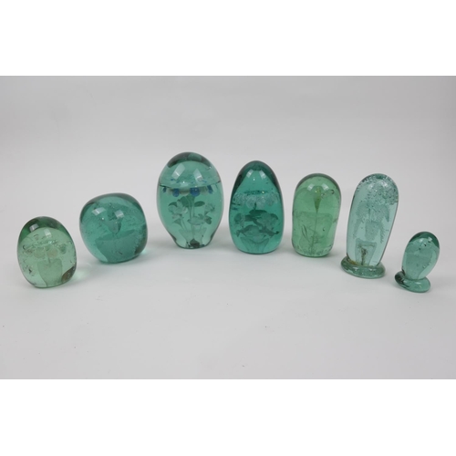 83 - Seven Victorian green glass dumps, each encasing a floral design and generally ovoid in shape, the l... 