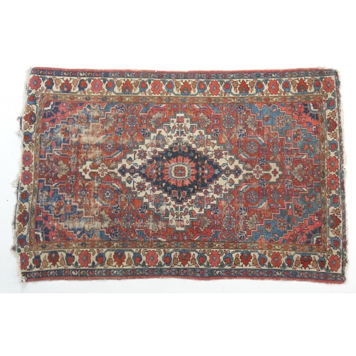 880 - Heriz woollen rug, having a central blue and fawn reserve with a red field dispersed with flowerhead... 