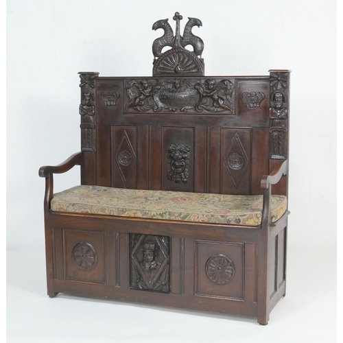 908 - Carved oak settle, the back centred with a dated carved oak panel with cherubs supporting an inscrib... 