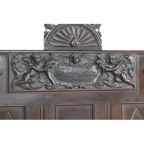 908 - Carved oak settle, the back centred with a dated carved oak panel with cherubs supporting an inscrib... 