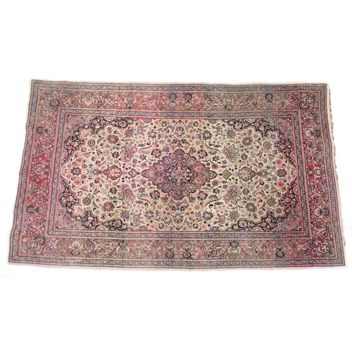 913 - Meshed woollen rug, the central pink medallion against a fawn field dispersed with palmettes, within... 