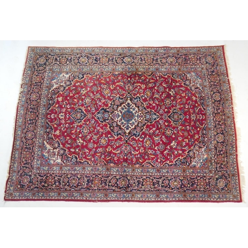 924 - Iranian Kirman style woollen carpet, central fawn and dark blue medallion within a red field dispers... 