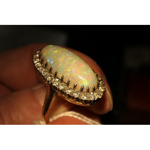 394 - Opal and diamond cluster ring, centred with a cabochon opal, 25mm x 10mm, depth approx. 13mm, in an ... 