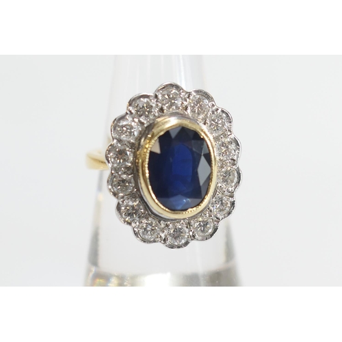 15 - Sapphire and diamond cluster ring, the oval cut sapphire approx. 9mm x 7mm, in a yellow gold collet ... 