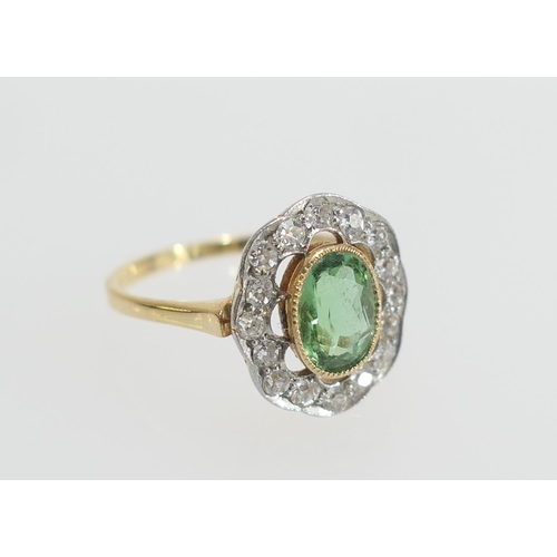 26 - Edwardian peridot and diamond cluster ring, the central oval cut peridot of approx. 7mm x 5mm, in a ... 