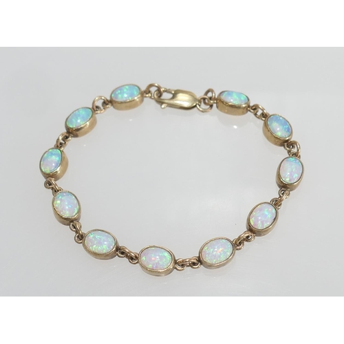 52 - Opal line bracelet in 9ct gold, set with eleven cabochon opals, each of approx. 7mm x 5mm, in collet... 