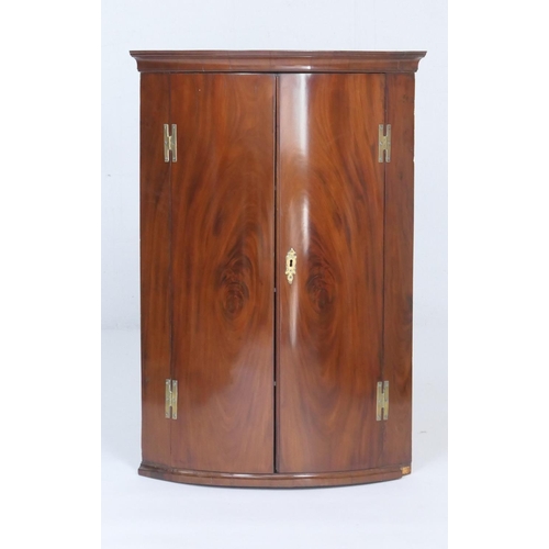 936 - George III mahogany bowfront corner cupboard, the well figured matched doors opening to three painte... 