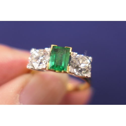 127 - Emerald and diamond three stone ring, the central emerald of approx. 0.75ct flanked by two old round... 