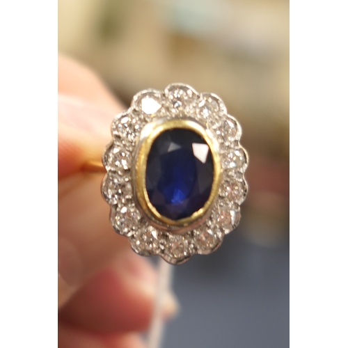 15 - Sapphire and diamond cluster ring, the oval cut sapphire approx. 9mm x 7mm, in a yellow gold collet ... 