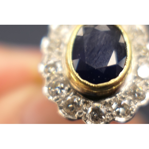 15 - Sapphire and diamond cluster ring, the oval cut sapphire approx. 9mm x 7mm, in a yellow gold collet ... 