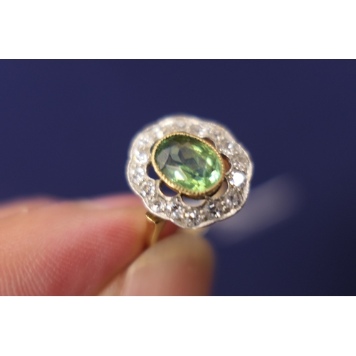 26 - Edwardian peridot and diamond cluster ring, the central oval cut peridot of approx. 7mm x 5mm, in a ... 