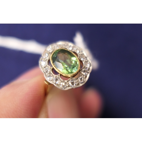 26 - Edwardian peridot and diamond cluster ring, the central oval cut peridot of approx. 7mm x 5mm, in a ... 