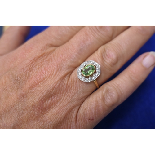 26 - Edwardian peridot and diamond cluster ring, the central oval cut peridot of approx. 7mm x 5mm, in a ... 