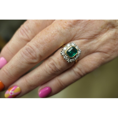 130 - Emerald and diamond cluster ring, the emerald of approx. 1ct, collet set in yellow gold and bordered... 