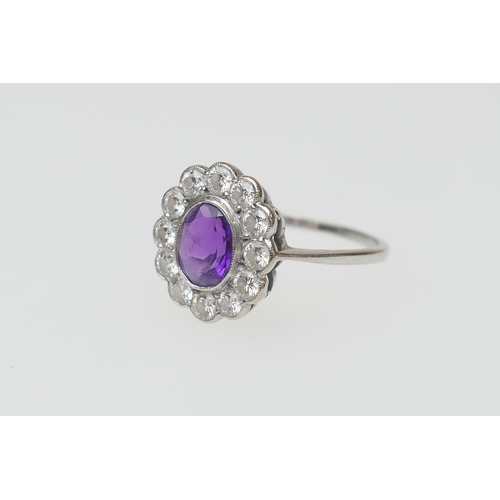 109 - Amethyst and diamond cluster ring, the oval cut central amethyst approx. 7mm x 5mm, in a millegrain ... 