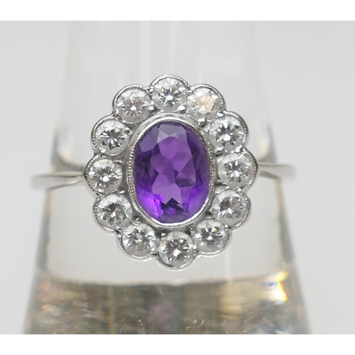 109 - Amethyst and diamond cluster ring, the oval cut central amethyst approx. 7mm x 5mm, in a millegrain ... 