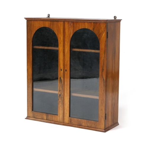 528 - Early Victorian rosewood wall cabinet, having two arched glazed doors opening to two adjustable shel... 