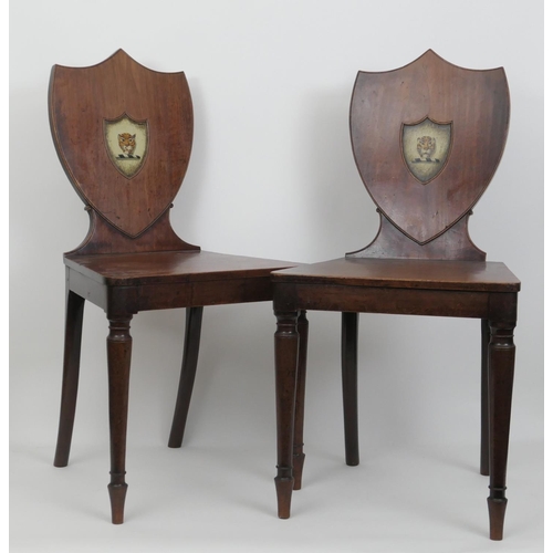 565 - Pair of George III mahogany armorial shield back hall chairs, circa 1790, the backs painted with a t... 