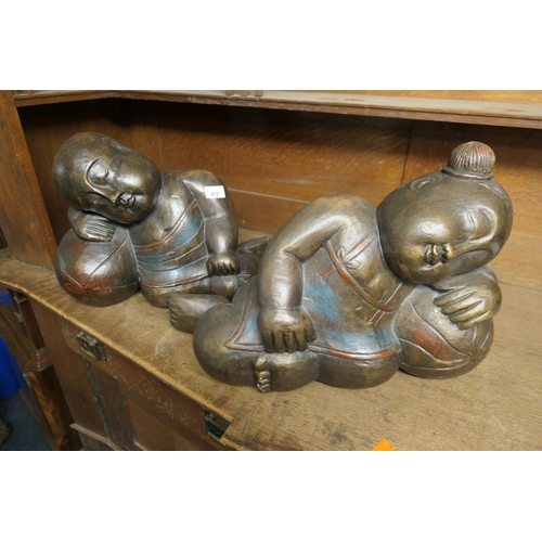 672 - Pair of Eastern carved wooden and partially painted figures of boys sleeping, length 47cm, height 34... 